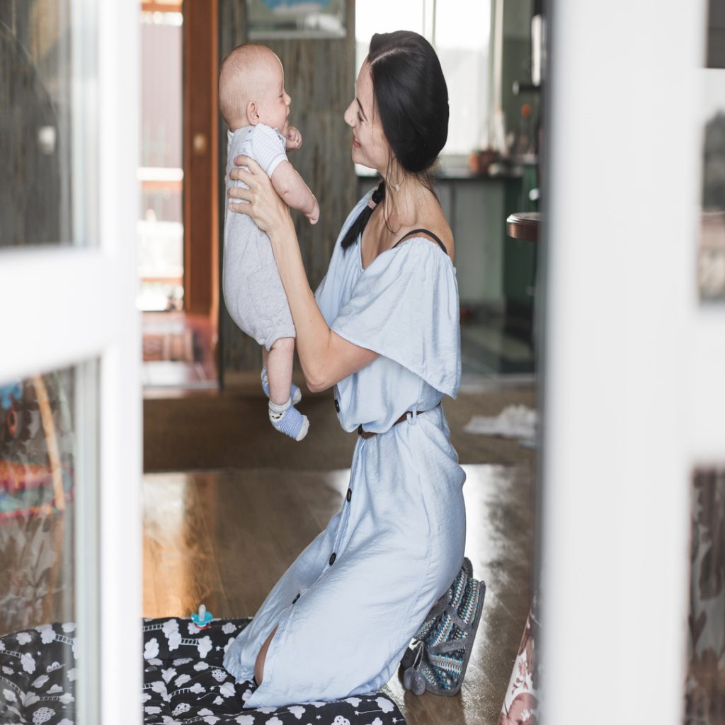 smiling-young-woman-playing-with-her-baby-home